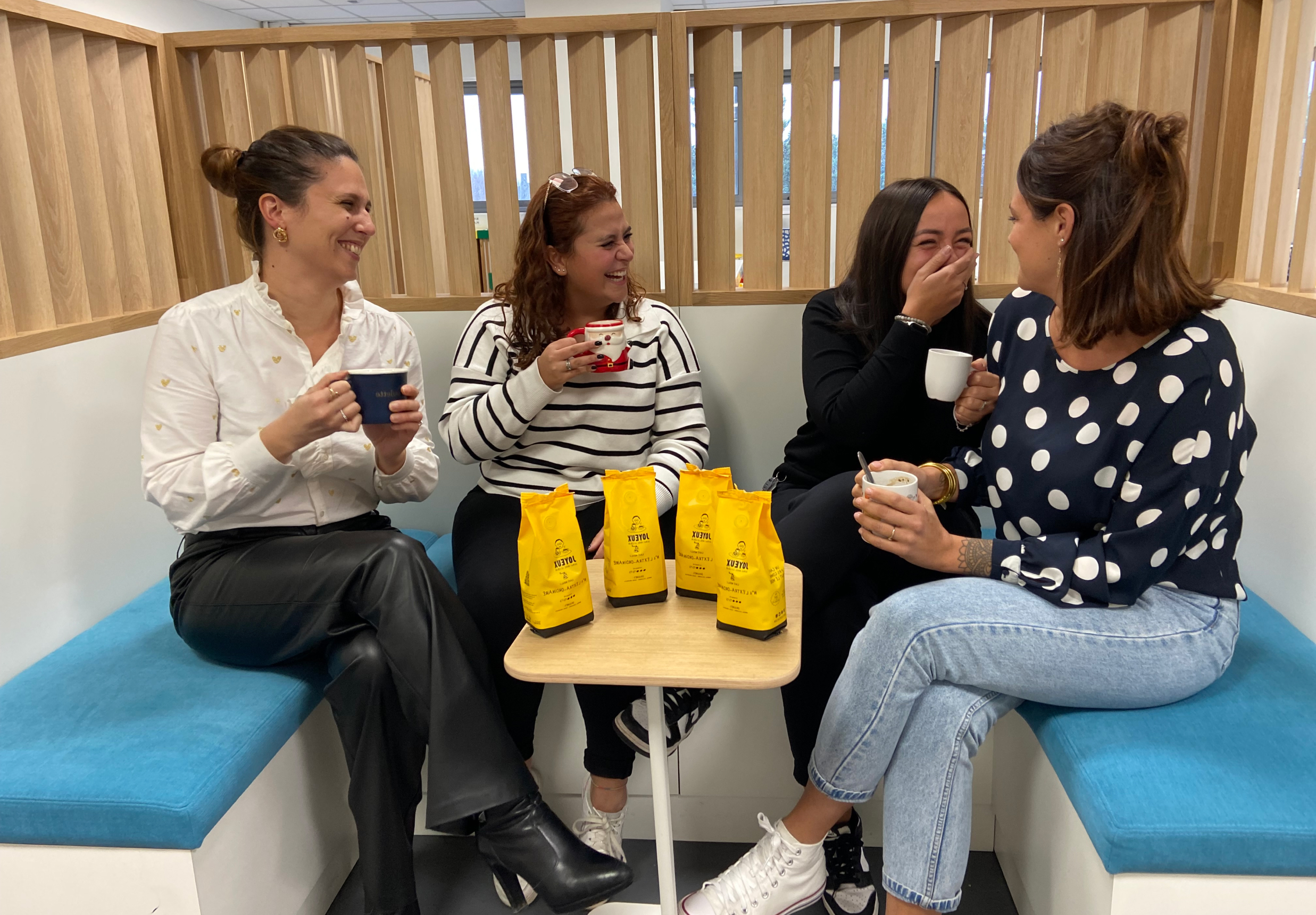 Quatre collaboratrices souriantes partageant un café